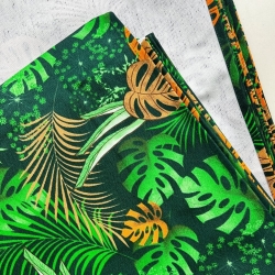 Liegestoff mit Monstera-Blättern in Orange auf schwarzem Hintergrund  